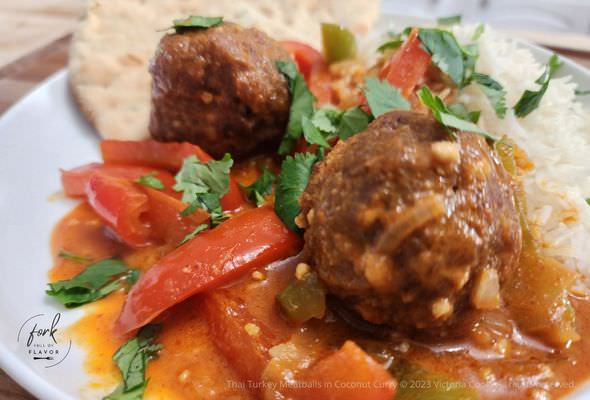 Plated Thai Turkey Meatballs in Coconut Curry over a bed of jasmine rice and a side of naan bread.