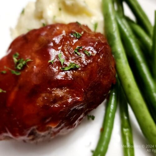 Mini meatloaves plated with mashed potatoes and cooked fresh green beans.