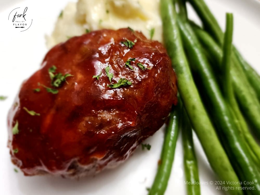 Mini meatloaves plated with mashed potatoes and cooked fresh green beans.