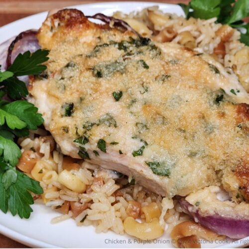 Baked Chicken & Purple Onion plated on a bed of homemade rice-a-roni and garnished with parsley