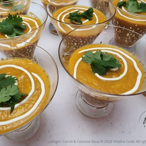 Ginger, Carrot & Coconut soup served in cocktail glasses with a swirl of sour cream and a sprig of cilantro