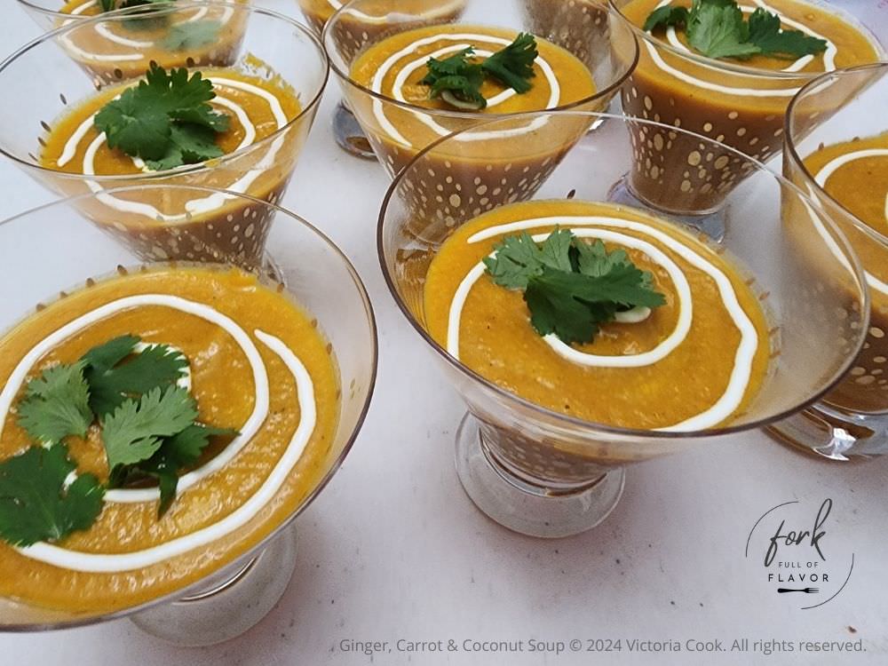 Ginger, Carrot & Coconut soup served in cocktail glasses with a swirl of sour cream and a sprig of cilantro