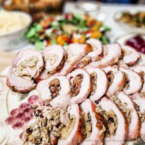 Three stuffed pork loins each with a different stuffing sliced and plated for serving.