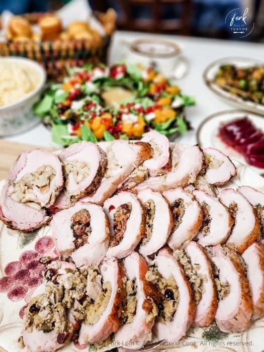 Three stuffed pork loins each with a different stuffing sliced and plated for serving.