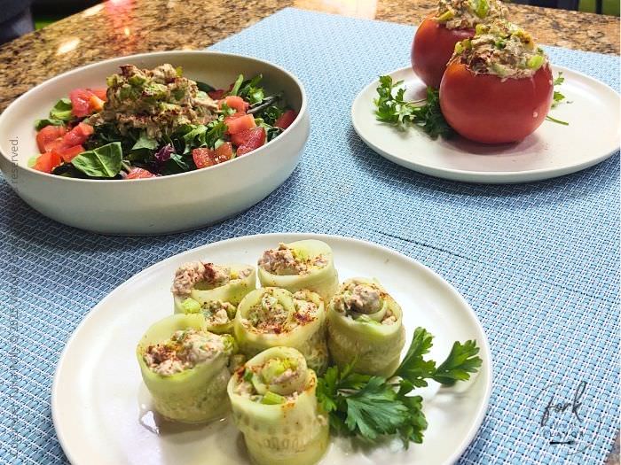 A plate of cumber tuna rolls, and the tuna mixture in a bowl on top of a salad and a third plate with tuna filled tomatoes